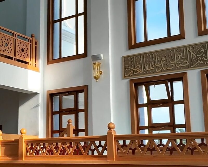 Daglicht valt door de hoge ramen van een gebedszaal met houten balustrades